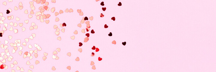 Banner with red confetti in a heart shape on a pink background. Concept with copy space.
