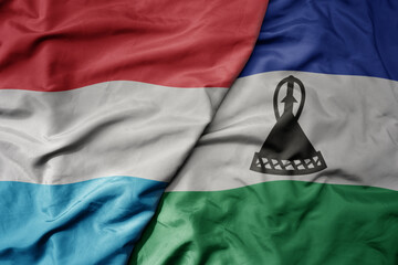 big waving national colorful flag of lesotho and national flag of luxembourg .