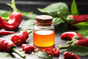 Gardinen Chilischoten Red chili pepper oil, tincture, extract or vinegar with fresh vegetables and leaves on black table, closeup, copy space, organic spicy food, hair and body healthy care concept  © spiegelka