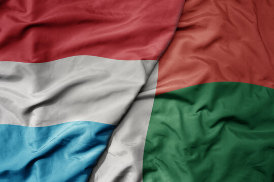 big waving national colorful flag of madagascar and national flag of luxembourg .