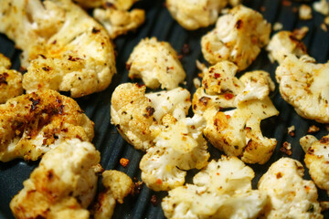 Grill showcasing mouth watering cauliflower cooking to perfection and sizzling with crispy goodness.