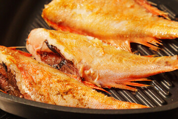 Sea bass sizzling away as they're expertly grilled to perfection in a warm.