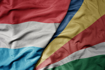 big waving national colorful flag of seychelles and national flag of luxembourg .