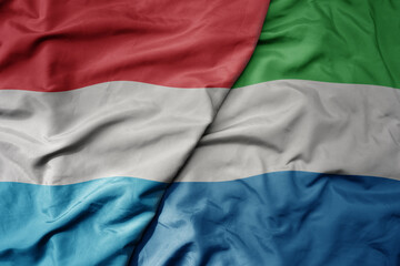 big waving national colorful flag of sierra leone and national flag of luxembourg .