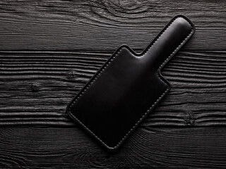 adult toy for sex over black wooden background. bdsm latex paddle for spanking