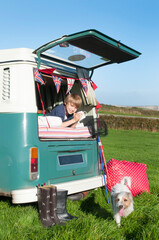 A boy in the back of a vintage campervan on a sunny day