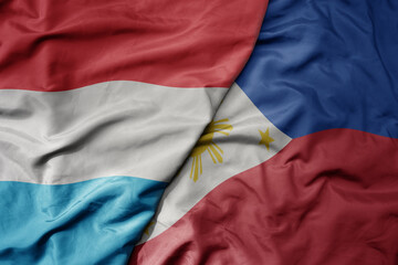 big waving national colorful flag of philippines and national flag of luxembourg .