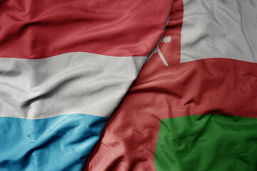 big waving national colorful flag of oman and national flag of luxembourg .