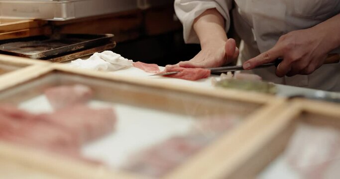 Cooking, hands and chef knife in a Japanese restaurant with catering, fish and dish in a kitchen. Menu, salmon and fine dining with sushi table, chop and person with food and sashimi for dinner