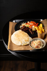 Overhead view of pita bread with meat and salad on black table - 746003045