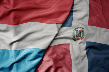 big waving national colorful flag of dominican republic and national flag of luxembourg .