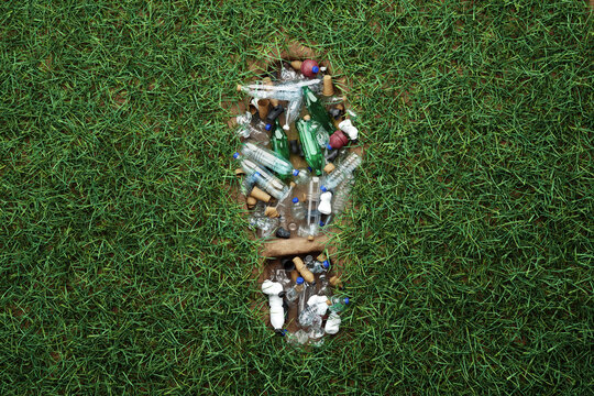 Concept plastic pollution, human footprint in green grass filled with trash, plastic waste, humanity's legacy. 3D rendering, Copy Space