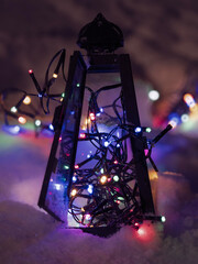 many lights strung in a lantern with snow on the ground
