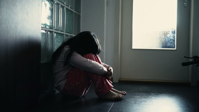 Lonely depressed child covering face while sitting on corridor at home, dramatic scene of lonely little girl struggling with mental illness in childhood