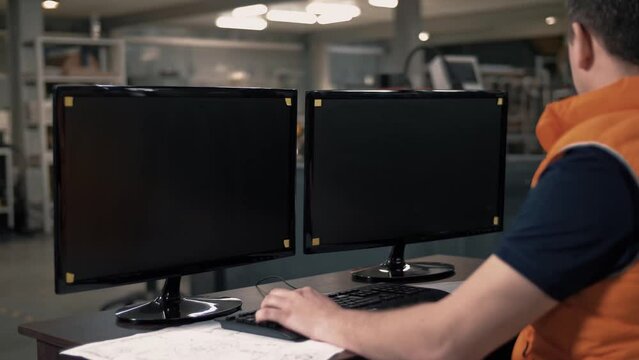 Engineer works on a computer behind monitors