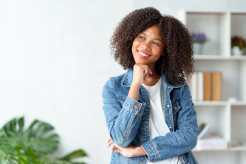 Smiling young woman with curly hair wearing a denim jacket. Casual fashion and lifestyle concept.