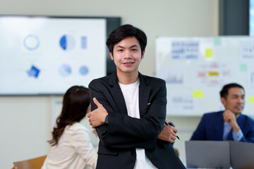 Confident asian businessman stand in a corporate office setting. Business success and confidence concept.