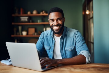 Man at home working on a laptop computer smiling