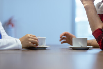 Hands and coffee cups on the table.