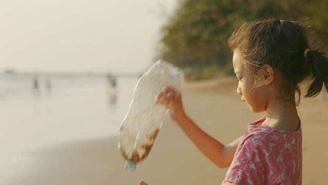 Asian kid girl, with copy space, who is holding empty plastic bottle and seeing with curiosity and thinking for generation problem shows concept of sea pollution and global warming for preservation.