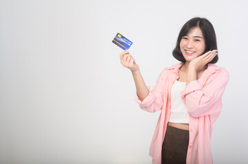 Asian smiling woman holding credit card over white background studio, shopping and finance concept.