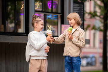 Fototapeta premium Children friends eating ice cream together while walking in the park