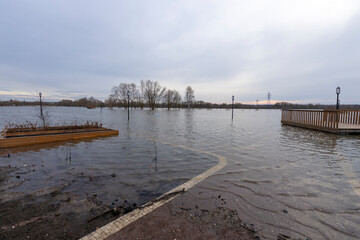 flooded park with paths and sidewalks, early spring flood, river overflowing its banks, environmental pollution, ecology