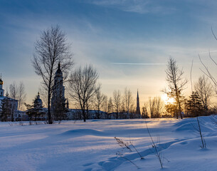 Winter landscape at sunset, frosty evening, view of ancient Slavic architecture.