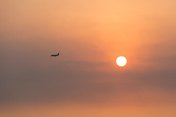 View of the sunset with a flying airplane