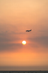 View of the sunset with a flying airplane