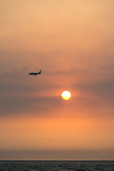 View of the sunset with a flying airplane