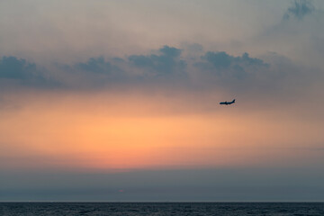 View of the sunset with a flying airplane