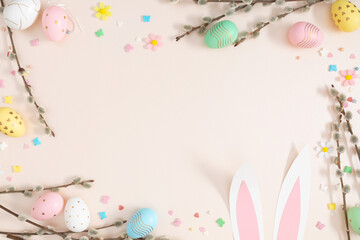 Fototapeta na wymiar Happy Easter concept. Flat lay, top view of Easter eggs, willow plant branches, rabbit on isolated pastel beige background