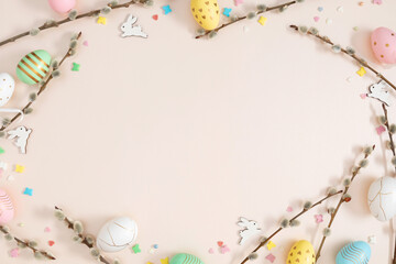 Happy Easter concept. Flat lay, top view of Easter eggs, willow plant branches, rabbit on isolated pastel beige background