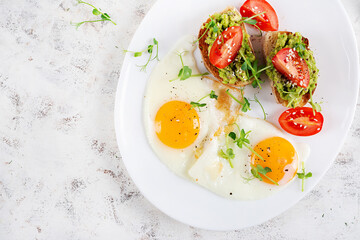 Keto breakfast. Fried eggs and toast with guacamole and tomatoes. Top view, flat lay