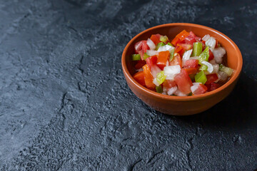 Creole sauce, made with bell peppers, tomatoes, onions in a bowl on a dark table.