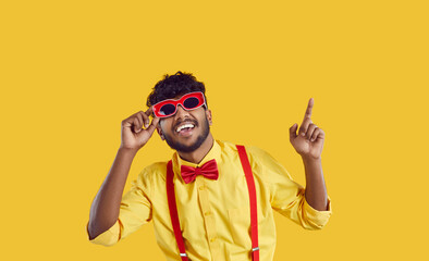 Funny man in party outfit dancing in studio. Portrait of happy young Indian guy in yellow shirt,...