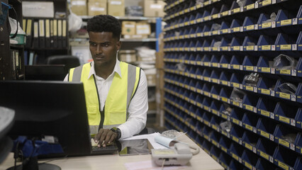 Black worker is checking the goods in the warehouse.