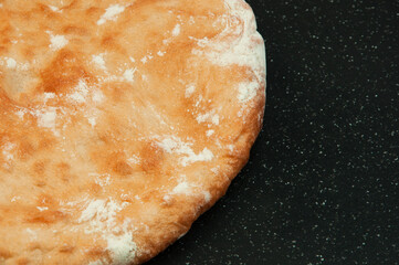 round georgian pita bread on a black background. round flat bread on a dark surface