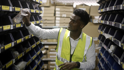 Black worker is checking the goods in the warehouse.