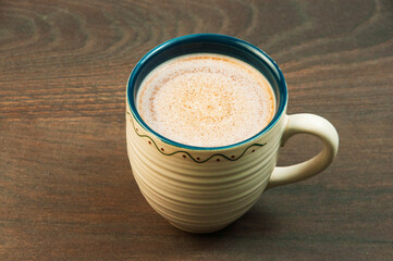 latte in a clay cup on the table. cocoa drink in a cup on a wooden background