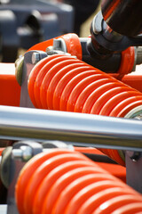 Hard orange spring made of steel. Part and detail of industrial or agricultural machine