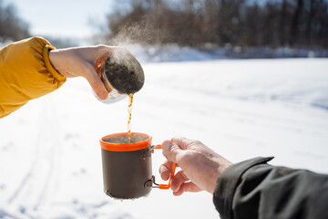 a person is pouring coffee into a mug in the snow