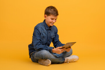 Teen boy using digital tablet while sitting cross-legged on floor in studio