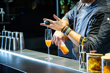 Barman prepara cokctail mimosa sobre la barra de un cocktail bar nocturno exclusivo muy delicioso