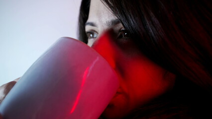 Pensive close-up woman drinking hot tea. Thoughtful gaze of person having leisure activity during cold weather