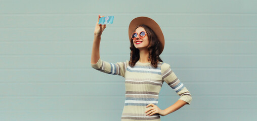 Portrait of stylish happy smiling young woman taking selfie with mobile phone