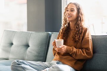 girl enjoys weekend sitting with warm cup of tea indoors