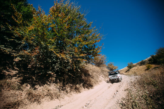 The jeep is driving along a dirt road in the mountains. Jipping along a fire road in the mountains. Car tours