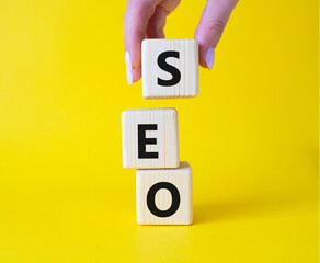 SEO - Search Engine Optimization symbol. Wooden blocks with words SEO. Businessman hand. Beautiful...